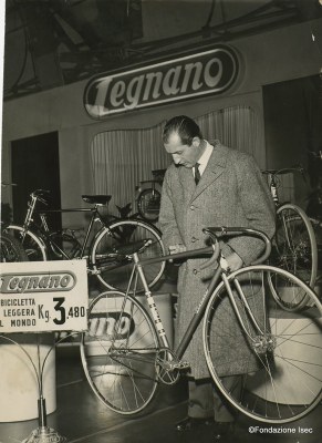 Milano, 33ª Mostra del Ciclo e Motociclo, 1955: Gino Bartali con la bicicletta più leggera del mondo -  Crediti: Fondazione Isec, Archivio fotografico "l'Unità"- redazione milanese